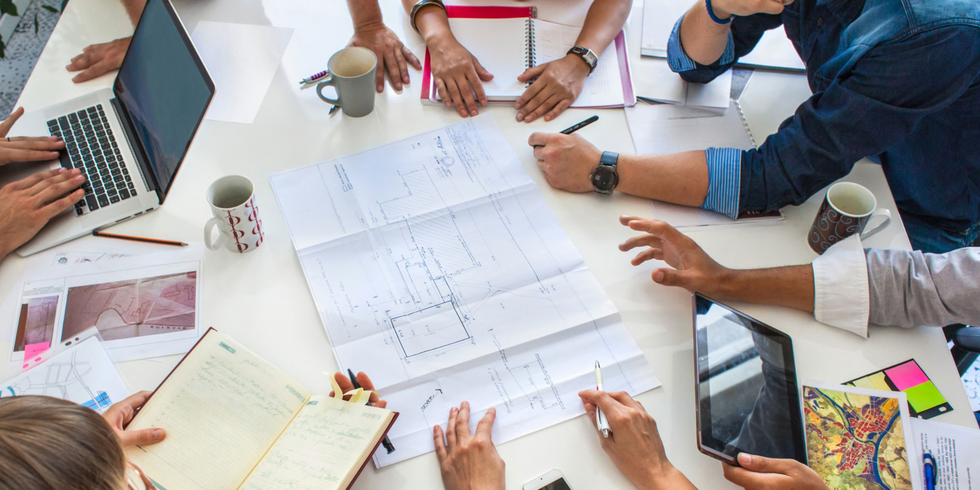 Colleagues look over housing blueprints during a meeting