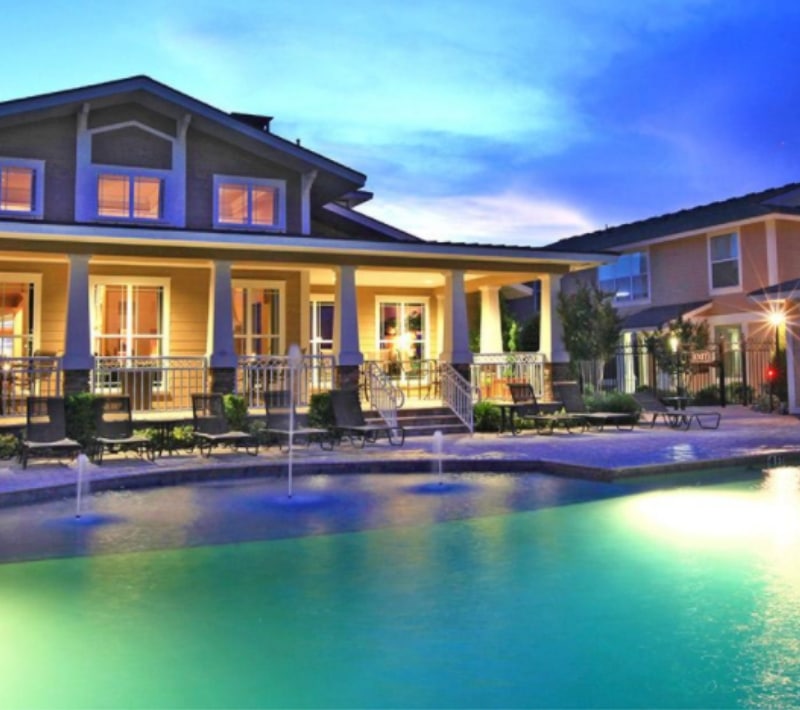 Clubhouse overlooking apartment pool area with fountains at dusk