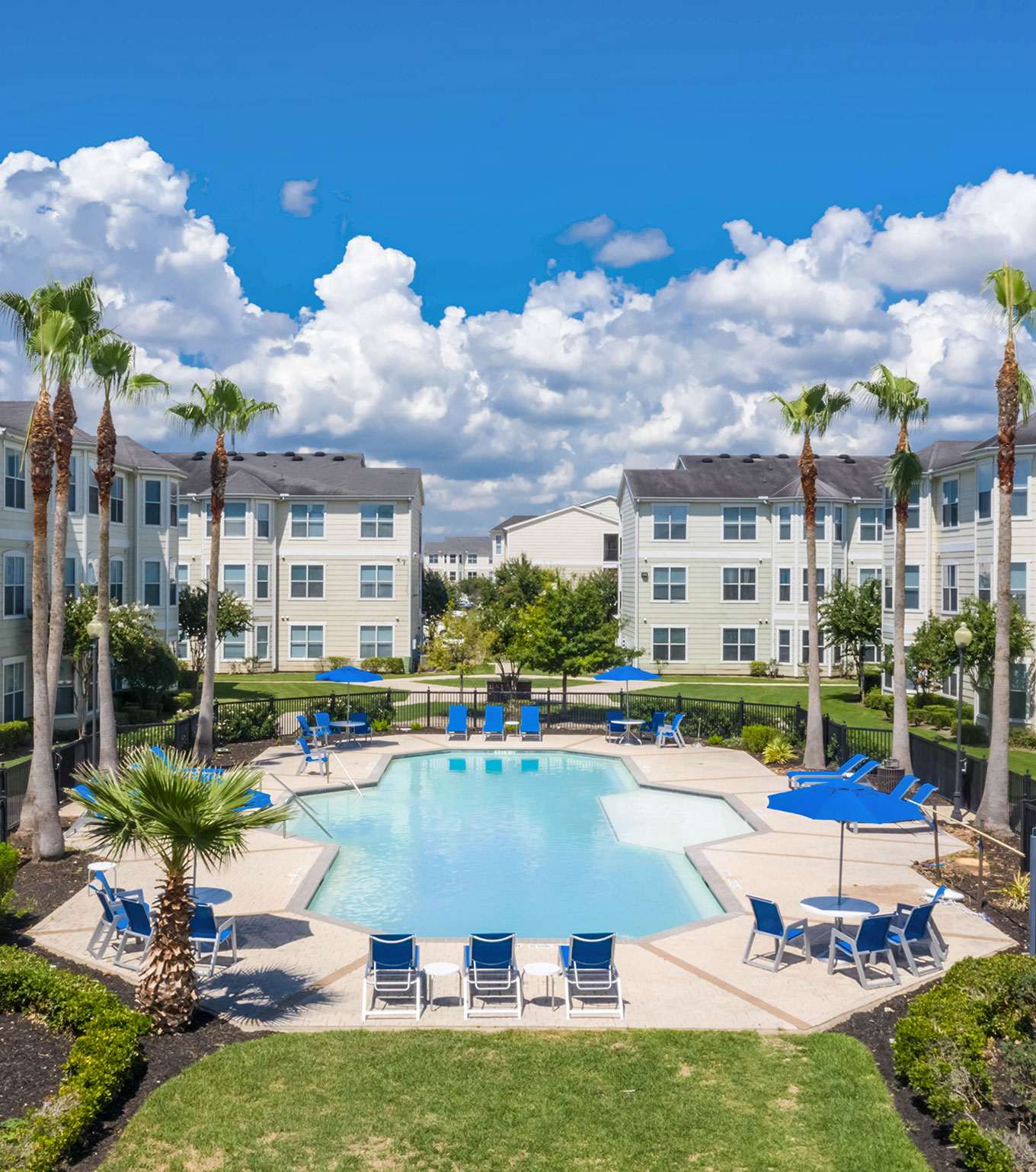 Apartment pool area with blue umbrellas and lounge chairs